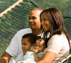 madre y padre con sus dos hijos sentados en una hamaca afuera