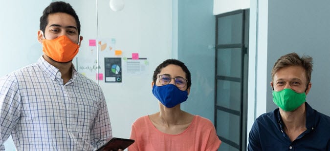 Three PHAP associates in masks pose for a photo while working in an office.