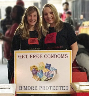 Margo Rosner and colleague near a sign the reads Get Free Condoms, B'More Protected