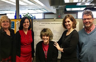 Photo: The NH Ryan White CARE Team poses in front of their improved billing case management outcomes poster.