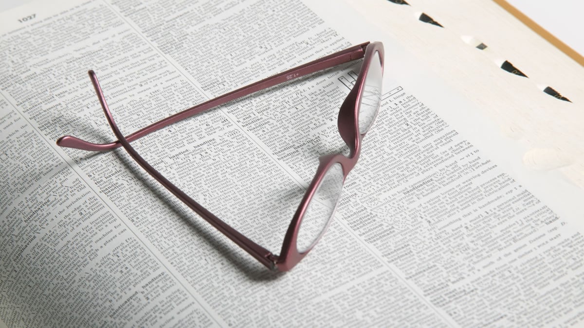 A pair of glasses laying on an open book