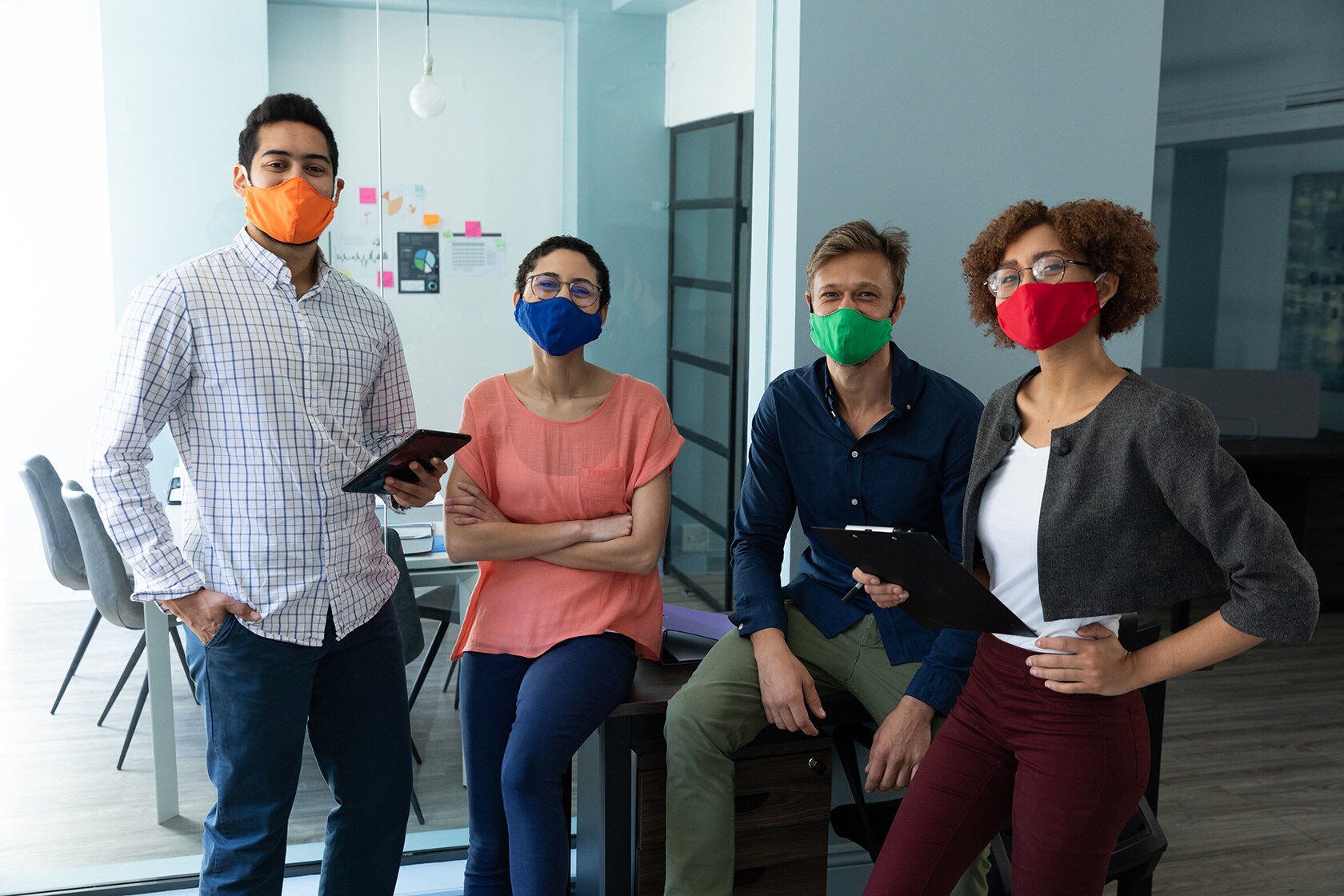 Professionals wearing masks and interacting in office setting 