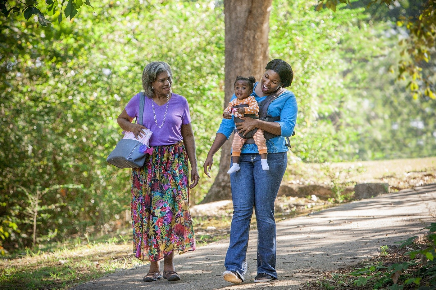 Two women and a baby walking together in a park.