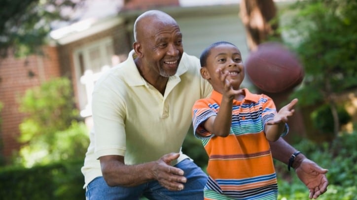 Older man playing football with his grandson.