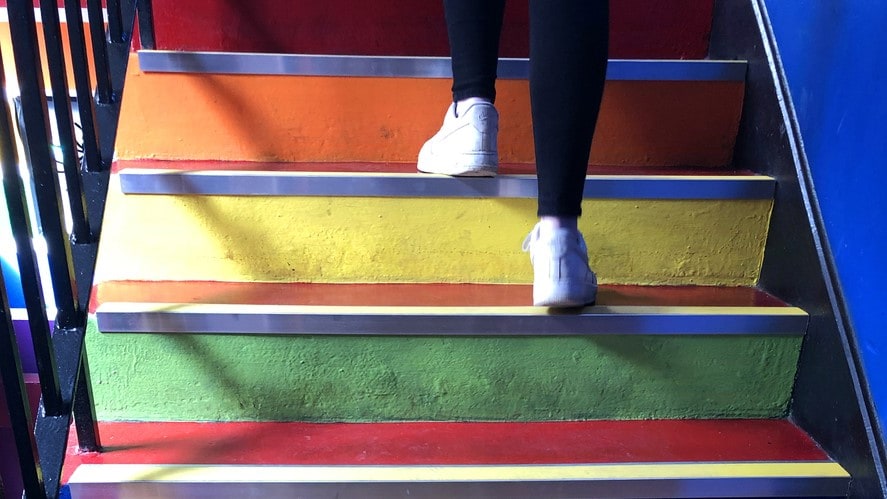 Feet of a person walking up a colorful stairwell.