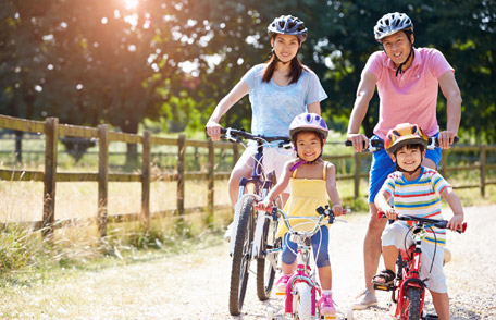 Familia de cuatro personas usando cascos y montando bicicletas afuera.