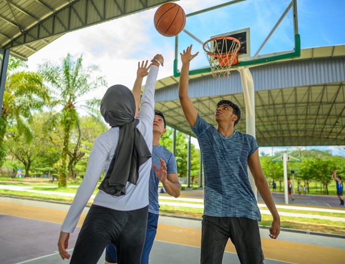 Two men and one woman playing basketball
