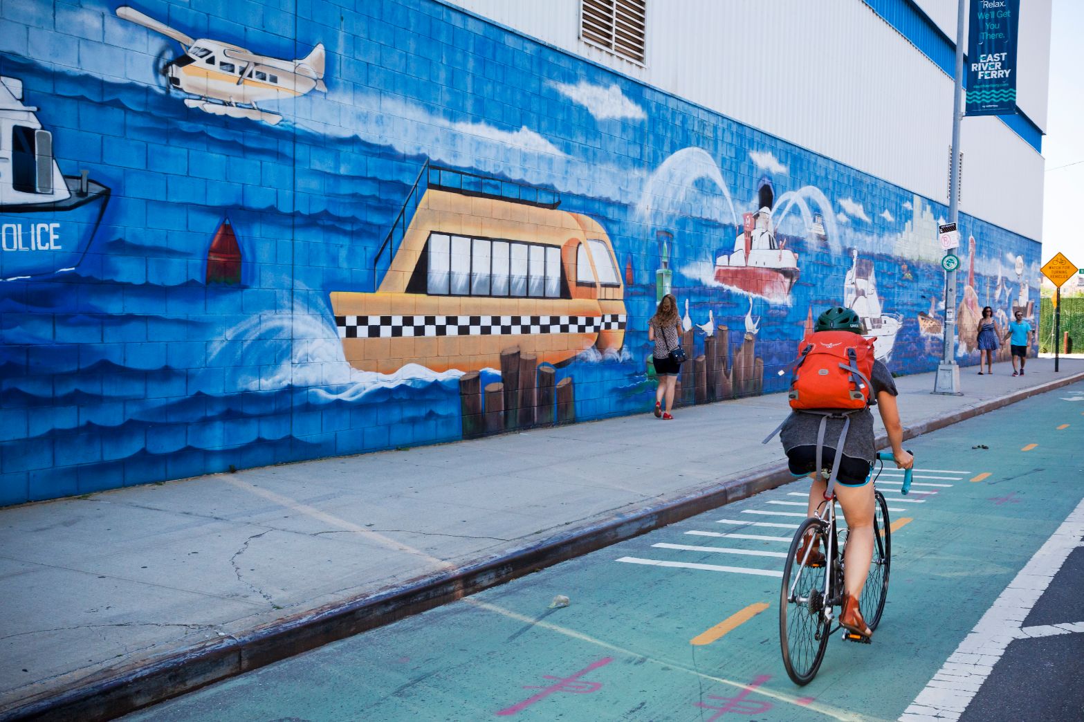 Woman biking with backpack by wall art