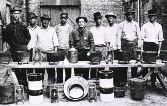 Rat Catchers in New Orleans; Group portrait of nine men standing behind a makeshift table