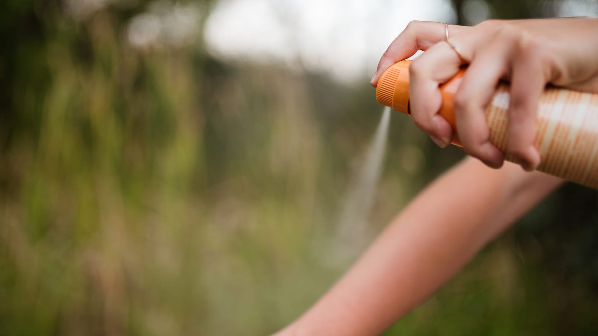 Insect repellent being sprayed on a person's arm.