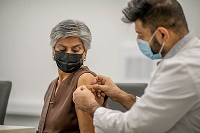 Doctor applies bandage to patient's arm after vaccination