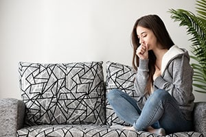 Woman coughs sitting on a couch