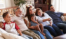Smiling family of six sitting together watching TV