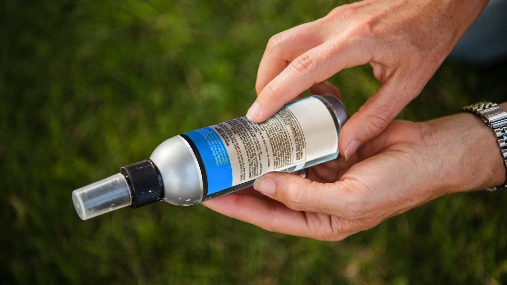 Person reading the ingredients on the back of a bottle of insect repellent