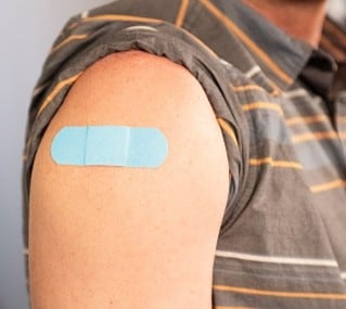 person with bandage on arm after vaccination