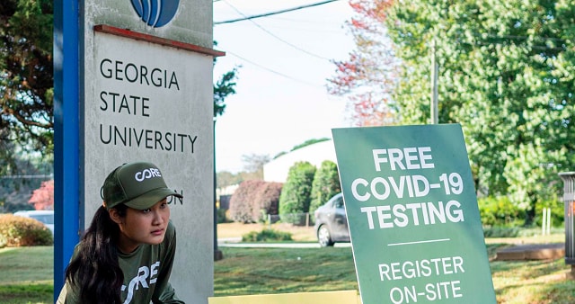 Woman standing in front of GSU and COVID testing signs.