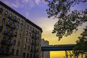 New York City subway next to a building with a purple and yellow sunset