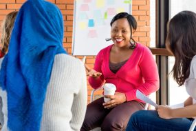 Diverse group of women in colorful clothes at a meeting, smiling and talking to each other