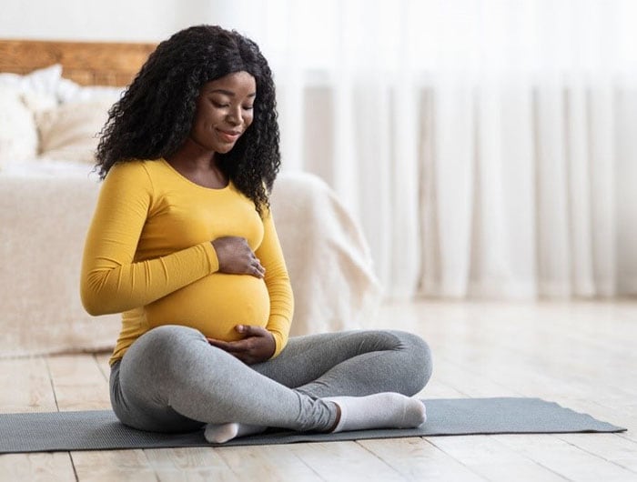 Pregnant African American women on exercise mat