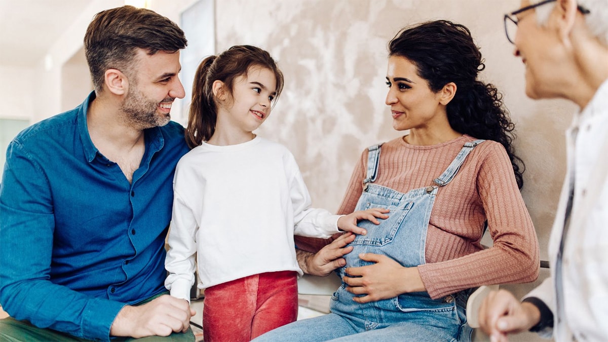 Family smiling at mom's pregnant belly