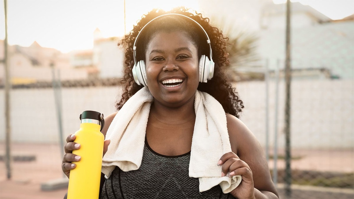 Smiling young woman with headphones and exercise gear