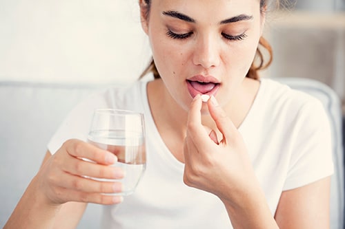 Young woman taking pill