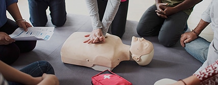 Group performing practice CPR on mannequin