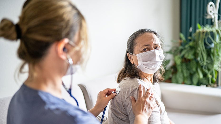 A healthcare worker listens to a patient's lungs.
