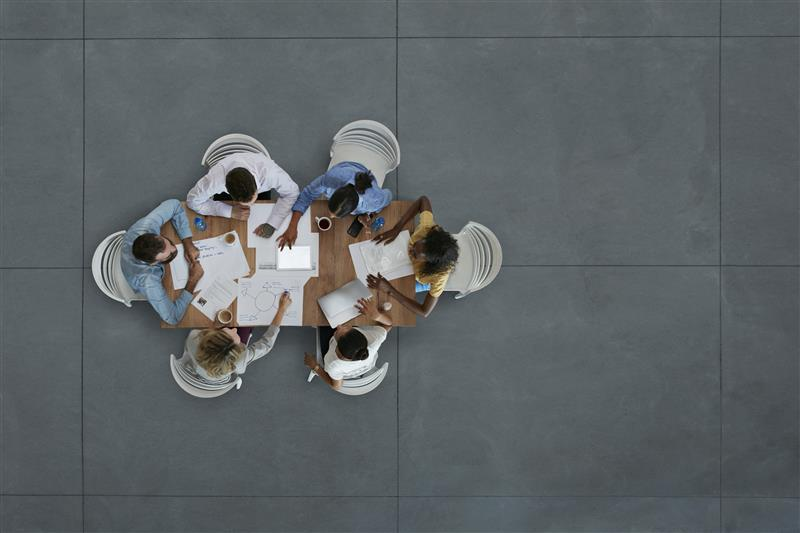 Arial view of group sitting around table with papers having a discussion.
