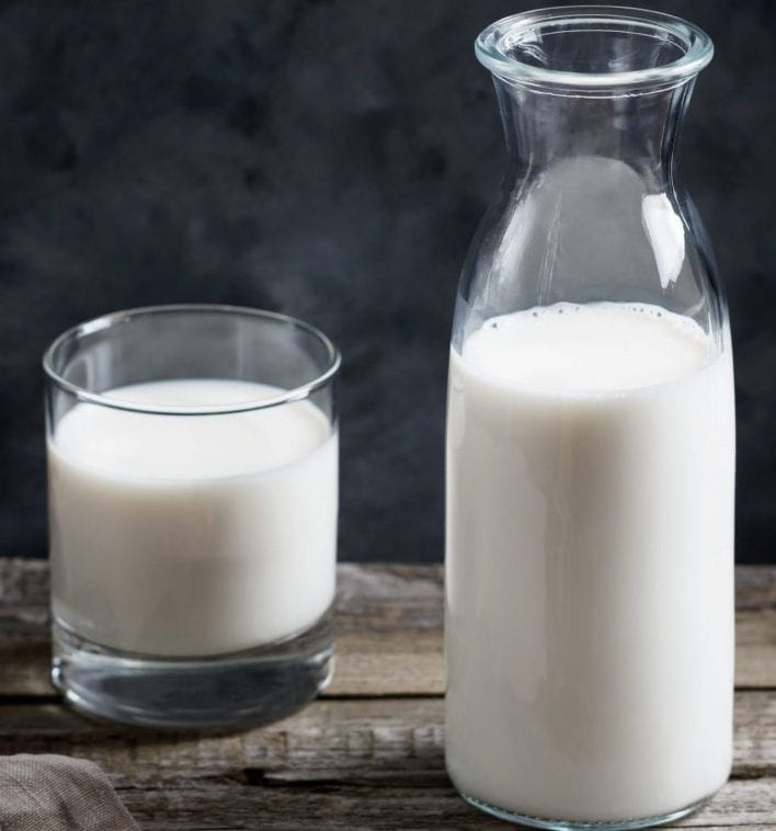 Close up of a glass of milk and an open glass milk bottle