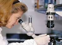 laboratory worker examining test results with a microscope