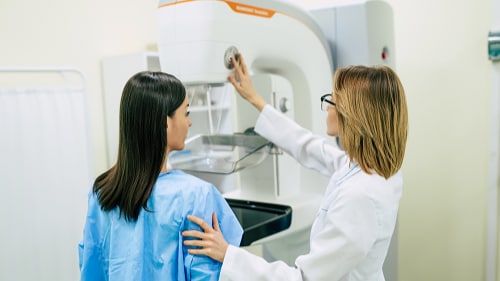 A doctor helping a female patient prepare for a mammogram.