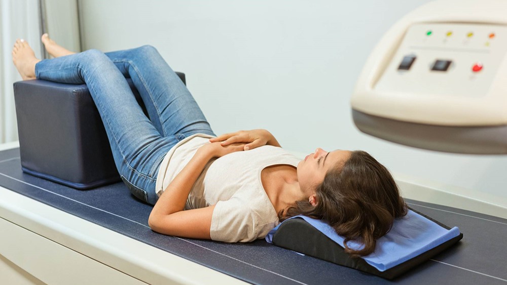 woman being scanned by at bone density scanner.