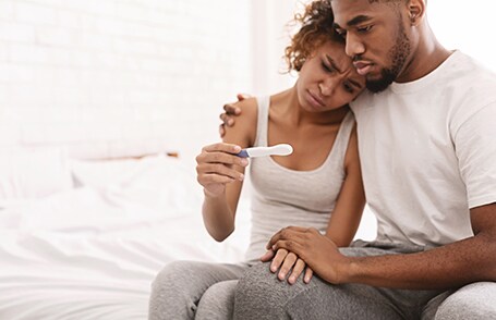 Man and woman both sad, hugging over a negative fertility test