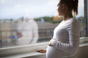 Imagen de una mujer embarazada mirando por la ventana