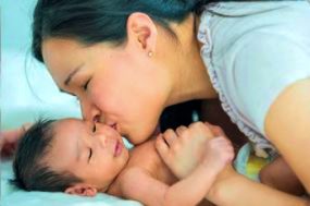 mother kissing infant