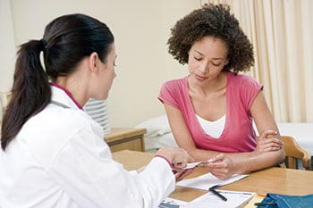 a woman at a desk with her healthcare provider