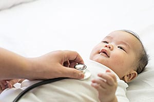 Médico examinando a un bebé con un estetoscopio.