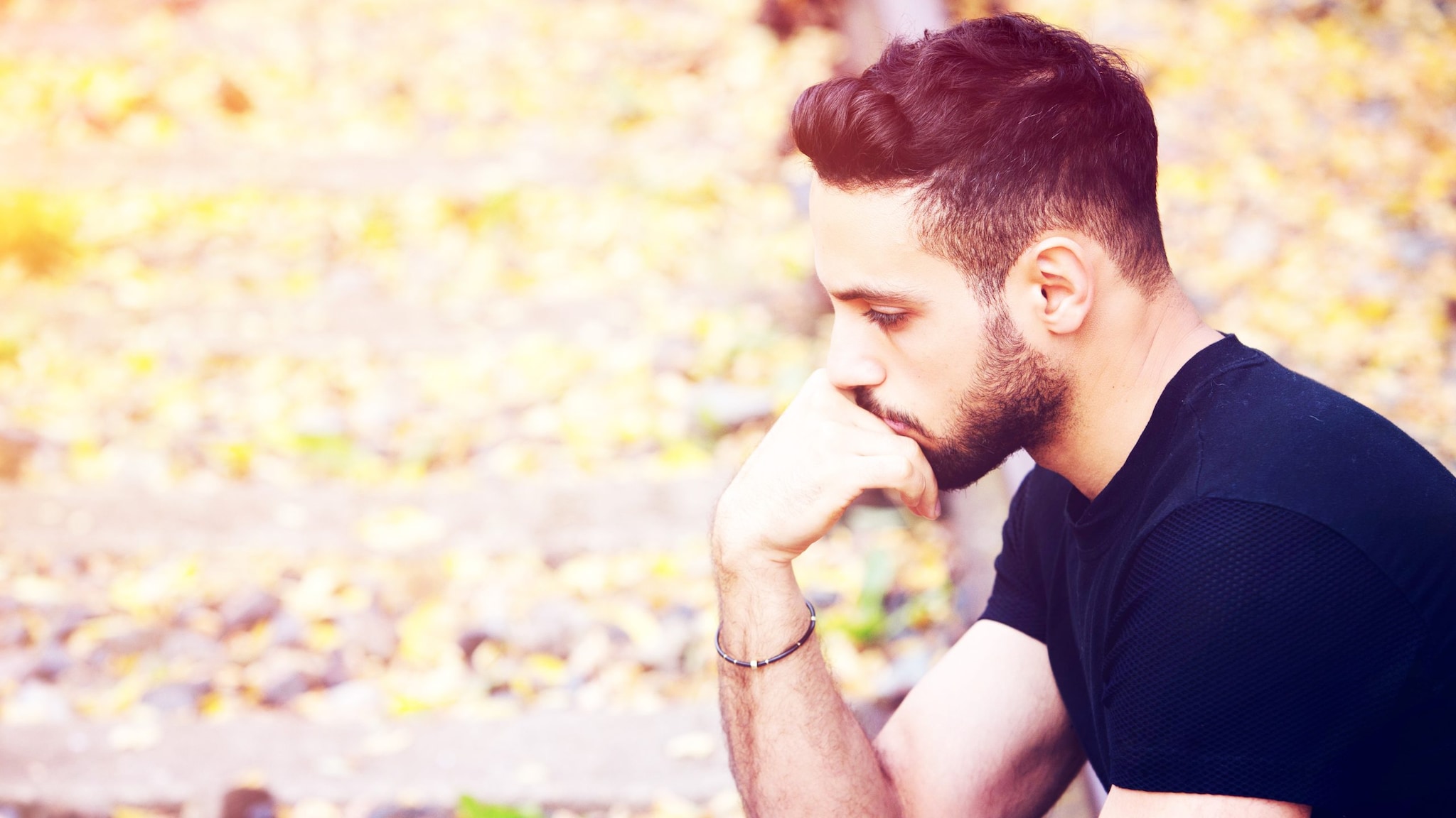 Young Man Sitting on Train Tracks Pensive