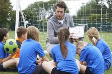 A soccer coach teaching children.