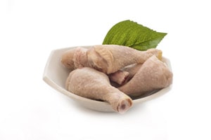Three uncooked chicken legs on a plate