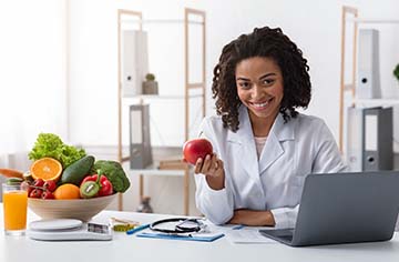 A female healthcare professional holding an apple.