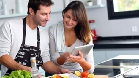 Couple cooking with fresh ingredients in home kitchen.