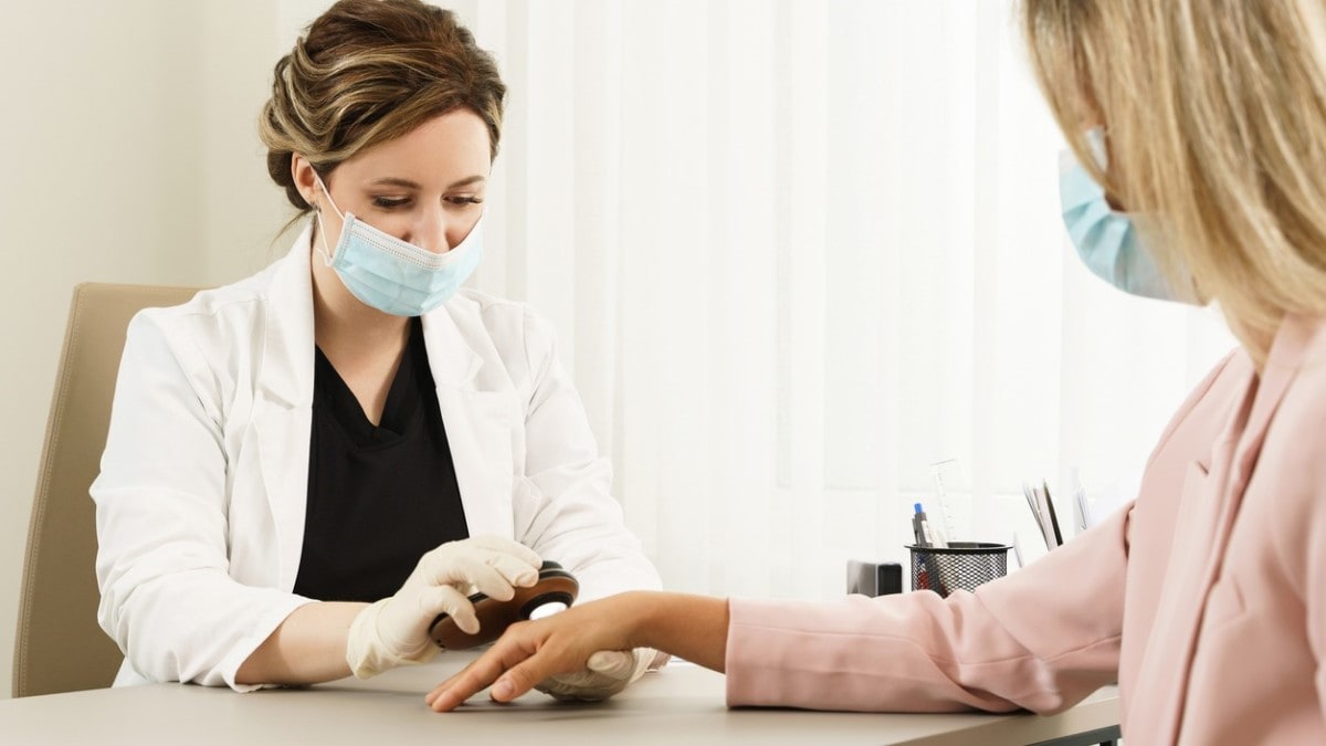 a doctor examining a mole on a woman's hand