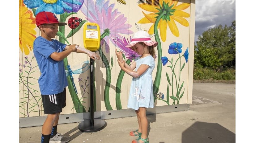 Kyle Davis y Hayley Davis se aplican protector solar de un dispensador en un parque de la ciudad de Reno.