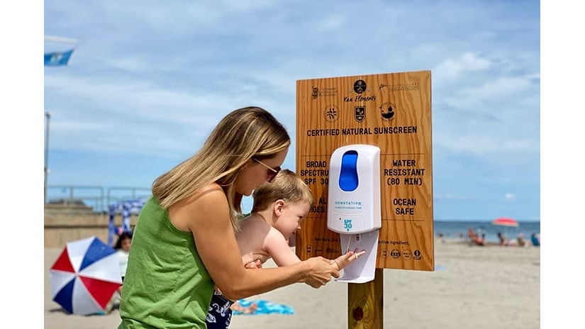 Terri Flori helps her son Kai apply sunscreen from a dispenser at Scarborough State Beach in Narragansett, Rhode Island.