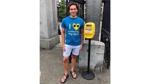 Joshua Sims Speyer standing next to a sunscreen dispenser