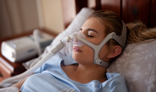 woman sleeping with a sleep apnea machine laying in bed