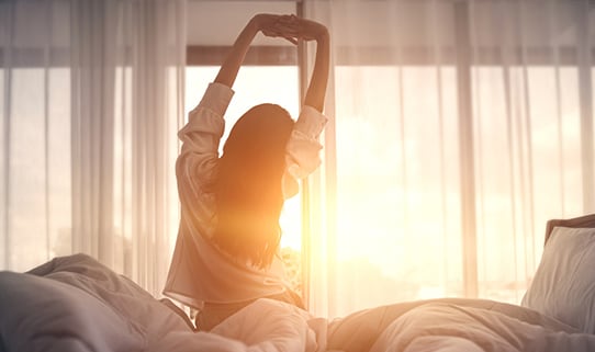 woman stretching and waking up on bed