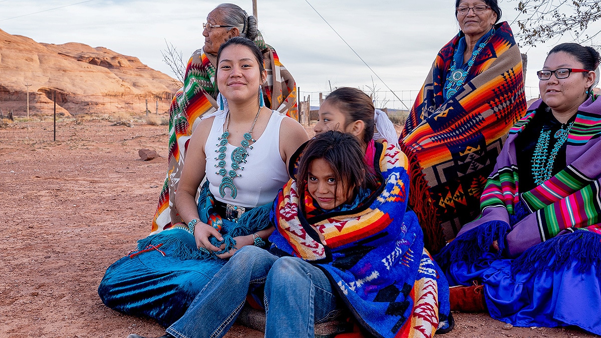 Multiple generations of female Navajos together, wrapped in customary blankets in Monument Valley.